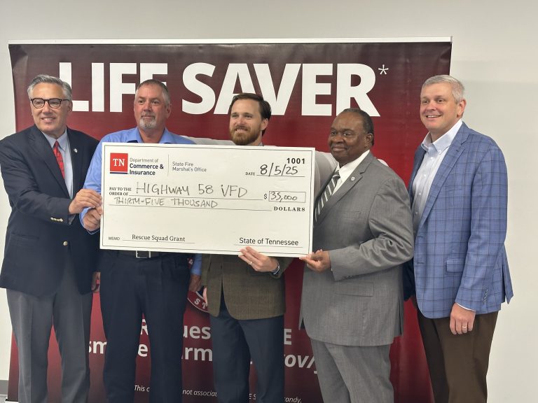 Five men in business attire stand in front of a red "LIFE SAVER" banner, holding a large ceremonial check for $35,000 made out to "Highway 58 VFD" from the State of Tennessee, dated 8/15/25.
